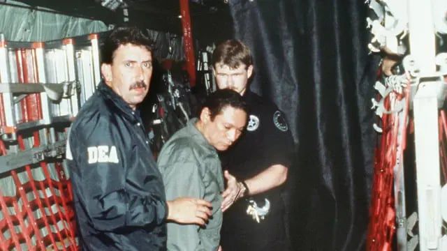 1990년 1월 3일 미국 마약단속국 직원들이 항복한 파나마의 독재자 마누엘 노리에가 장군을 체인에 묶어 미 군용기에 태우고 있다.