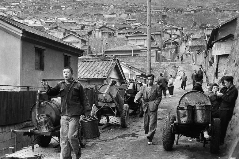 전쟁 후 부산은 북한 뿐 아니라 전국에서 온 피란민들이 많던 도시였다. 드럼통을 개조한 손수레들 사이로 양복에 흰 고무신을 신고 걸어가는 남자가 인상적이다./©한영수 부산 1956-1963