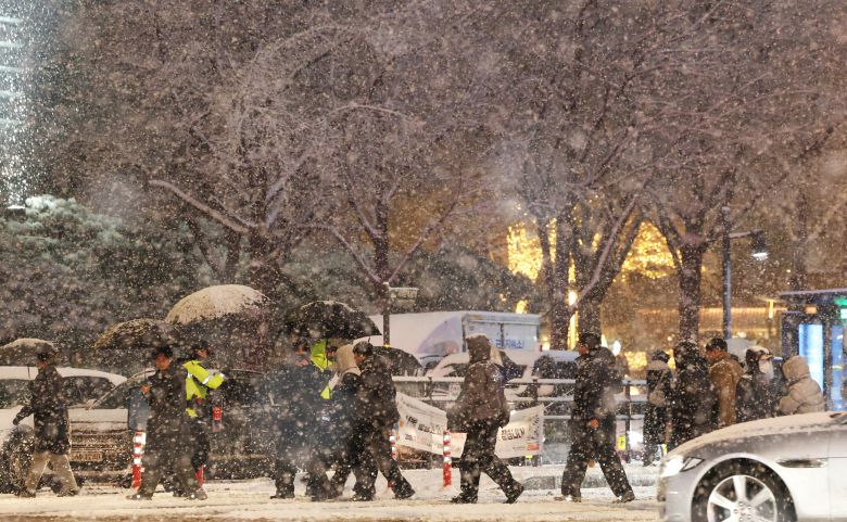 수도권에 폭설이 쏟아진 4일 서울 광화문 광장에서 시민들이 눈을 피하기 위해 발걸음을 서두르고 있다. /장경식 기자