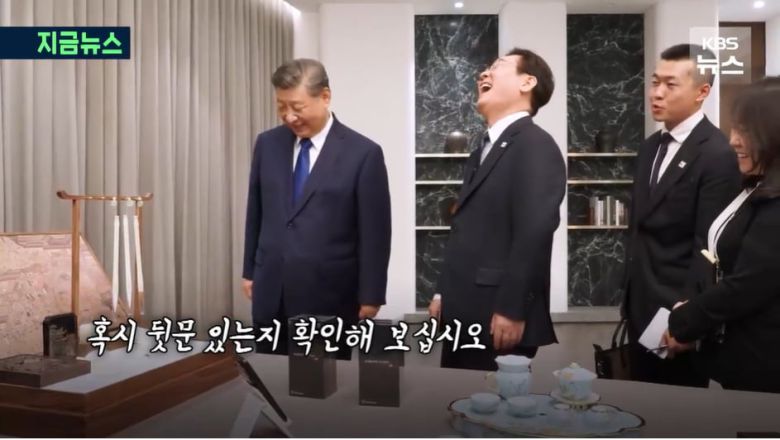 이재명 대통령과 시진핑 중국 국가주석이 선물을 교환하며 대화하고 있다. 이 대통령이 중국의 샤오미 휴대폰 선물에 '통신보안'을 언급하자, 시 주석은 "혹시 뒷문 있는지 확인해 보십시오"라고 응수했다./KBS