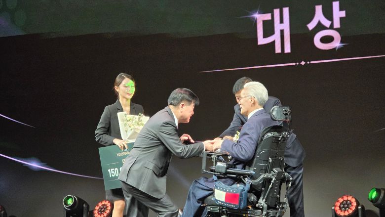지난달 'HD현대 1% 나눔재단'의 아너상 시상식에서 장애가 있는 수상자에게 무릎을 꿇고 상패를 전달하고 있는 권오갑 명예회장(왼쪽). /HD현대 제공