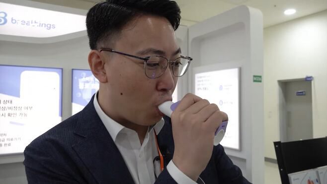 이인표 대표가 불로 기기를 이용해 폐 나이를 측정하는 모습. 입으로 바람을 세게 불면 기기 내부에 있는 센서가 호흡의 양과 압력을 측정한다. 호흡 세기나 길이에 따라 폐활량, 폐 근력, 폐 지구력, 폐 나이 등을 추정한다. /이들의 순간 캡처