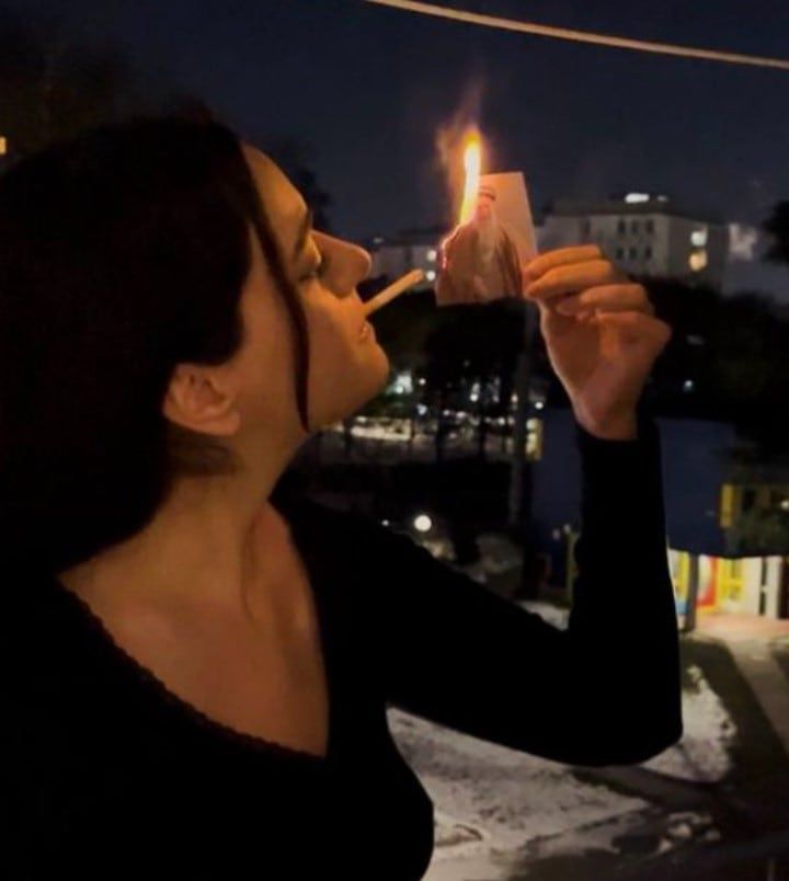 이란 최고지도자 아야톨라 알리 하메네이의 사진을 불 태우고 담뱃불로 쓰는 여성 ./ 엑스(X)