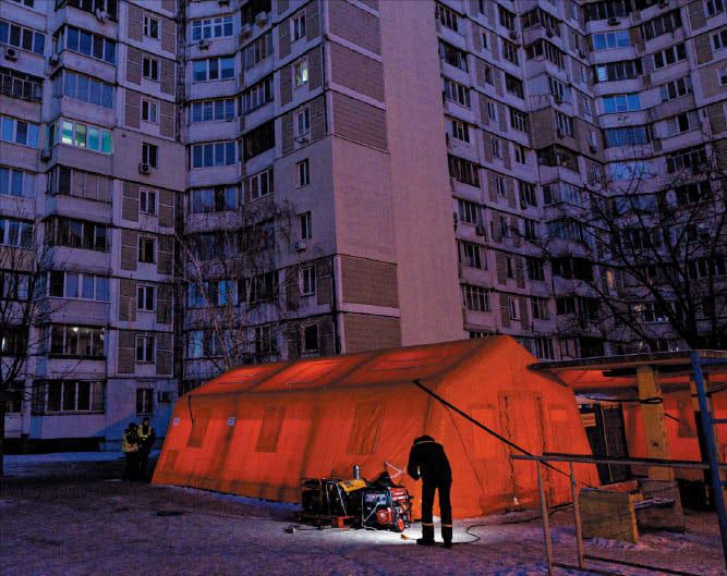 정전된 아파트와 긴급 구호 텐트  20일 러시아의 공습으로 정전된 우크라이나 수도 키이우의 아파트 앞에 임시 텐트가 설치돼 있다./로이터 연합뉴스