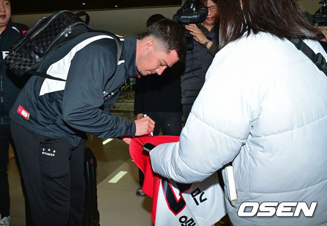 [OSEN=김포공항, 박준형 기자] 2026시즌 스프링캠프 나서는 KIA 코칭스태프와 외국인 선수들이 22일 김포국제공항을 통해 일본 아마미오시마로 출국했다. 지난해 미국 캘리포니아 어바인에서 훈련했던KIA는 일본 가고시마현의 외딴섬인 아마미오시마로 1차 훈련지로 정했다. 심재학 KIA 단장은 “미국에서 훈련해서 원하던 결과를 얻지 못했다”면서 “시차 등을 고려해도 일본이 낫다고 평가했다. 현지 실사를 했을 때 훈련에만 집중하기 딱 좋은 환경이었다”고 밝혔다.KIA 올러가 팬에게 사인을 해주고 있다.     2026.01.22 / soul1014@osen.co.kr