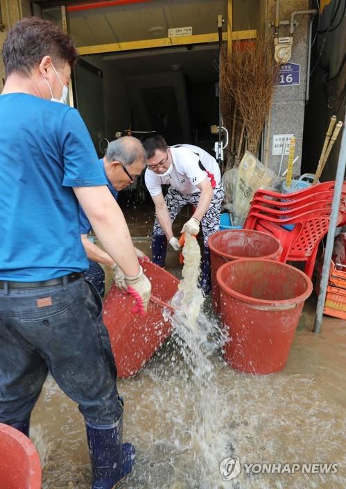 빗물 퍼내 수해 복구(구례=연합뉴스) 박철홍 기자 = 9일 오전 전남 구례군 구례읍 수해를 당한 오일장 상인들이 수도마저 끊겨 빗물을 퍼내 집기를 씻고 있다. 2020.8.9 pch80@yna.co.kr