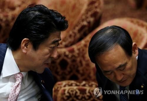 2014년 2월 20일 일본 중의원 예산위원회에서 아베 신조 일본 총리가 스가 요시히데 관방장관에게 귀엣말을 건네고 있다. [로이터=연합뉴스 자료사진]