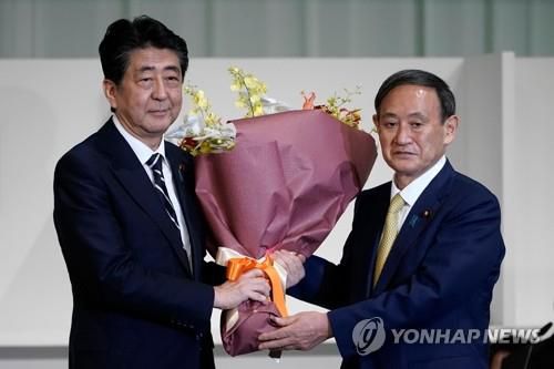 (도쿄 AFP=연합뉴스) 스가 요시히데(菅義偉) 일본 총리가 총리로 선출되기 이틀 전인 14일 도쿄 한 호텔에서 열린 집권 자민당 총재 선거에서 당선된 후 아베 신조(安倍晋三) 당시 총리에게 꽃다발을 주고 있다.
