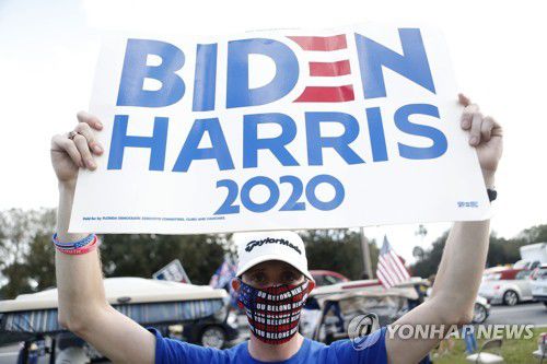 지난 23일(현지시간) 미국 플로리다에서 한 주민이 조 바이든 민주당 대선후보 지지 플래카드를 들고 있다.[AFP=연합뉴스]