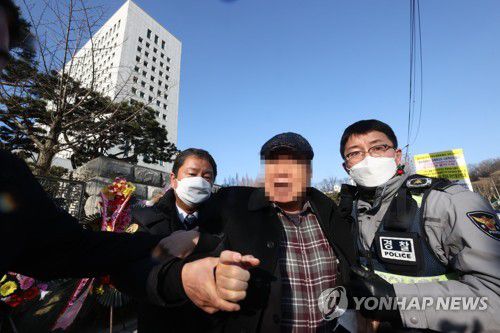 경찰에 연행되는 대검 앞 방화 용의자(서울=연합뉴스) 류영석 기자 = 5일 오전 서울 서초구 대검찰청 앞에서 윤석열 검찰총장 응원화환에 불을 붙인 남성이 경찰에 연행되고 있다. 2021.1.5 ondol@yna.co.kr