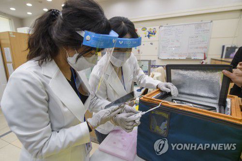 광주 지역 보건소에서도 백신 이송 훈련(광주=연합뉴스) 박철홍 기자 = 국내에서 생산된 아스트라제네카(AZ)사의 신종 코로나바이러스 감염증(코로나19) 백신을 전국 보건소로 안전하게 배송하는 모의훈련이 19일 진행됐다. 사진은 이날 오후 광주 북부보건소에서 수송 요원이 전달한 훈련용 백신을 보건소 직원들이 확인하고 있는 모습이다. 2021.2.19 pch80@yna.co.kr