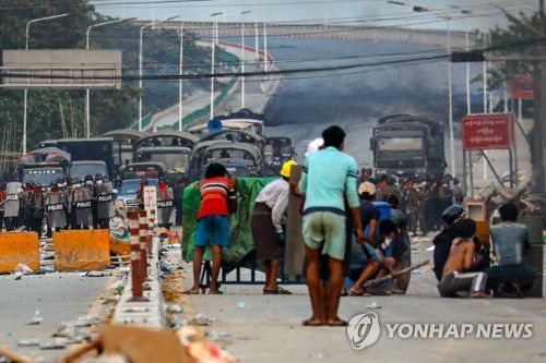 방패 뒤에 몸 숨긴 채 경찰과 대치하는 미얀마 시위대[양곤 AFP=연합뉴스 자료 사진]