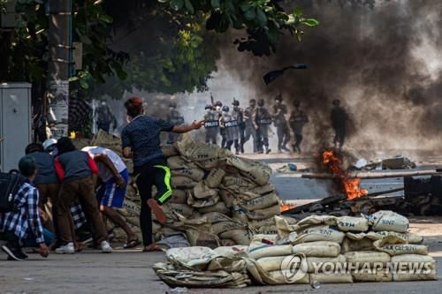 양곤 시내에서 군경과 대치하면서 바리케이드 뒤로 숨은 시위대. 2021.3.17[AFP=연합뉴스]