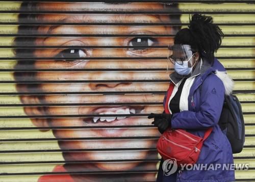지난달 25일 영국 런던에서 한 여성이 셔터 문 옆을 지나고 있다.[AP=연합뉴스]