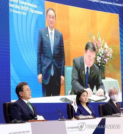 문재인 대통령이 2020년 11월 15일 청와대에서 열린 세계 최대규모의 자유무역협정(FTA)인 '역내포괄적경제동반자협정(RCEP)' 협정문 서명식에서 일본 정부의 서명 장면을 화상 중계로 지켜보고 있다. 중계된 화면을 보면 가지야마 히로시(梶山弘志) 일본 경제산업상이 서명하고 있고 뒤에 스가 요시히데(菅義偉) 일본 총리가 서 있다. [연합뉴스 자료사진]