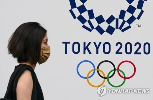 (도쿄 EPA=연합뉴스) 일본 10개 광역자치단체에 신종 코로나바이러스 감염증(코로나19) 긴급사태가 발효 중인 가운데 28일 도쿄에 설치된 도쿄올림픽 홍보물 근처에서 마스크를 쓴 사람이 이동하고 있다.