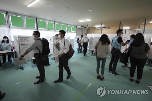 (도쿄 AP=연합뉴스) 8일 일본 도쿄도(東京都)의 옛 쓰키지(築地) 시장 부지에 마련된 대규모 접종센터에서 소방대원 등이 신종 코로나바이러스 감염증(코로나19) 백신을 맞기 위해 대기 중이다.