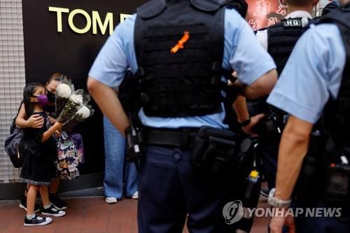 2일 한 여성이 자녀와 함께 경찰관 피습 사건이 발생한 홍콩 코즈웨이베이를 찾아 헌화 하려하자 경찰이 검문검색을 펼치는 모습. [로이터=연합뉴스]