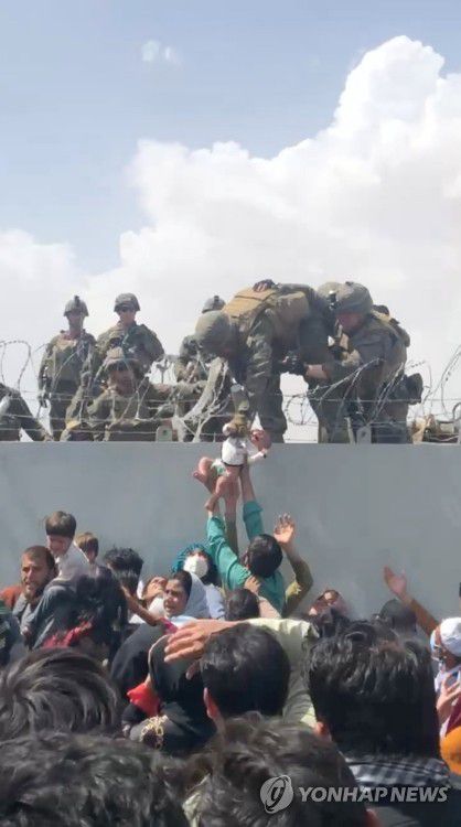 '필사의 탈출'…카불공항 담장 위로 미군에 건네지는 아기(카불 로이터=연합뉴스) 이슬람 무장세력 탈레반이 장악한 아프가니스탄 수도 카불의 국제공항에서 19일(현지시간) 국외로 탈출하려는 아프간 주민이 공항 담 위에서 경비를 서는 미군에게 아기를 건네고 있다. 외신은 수천 명의 아프간인이 탈출 기회를 엿보며 공항 주변에서 천막생활을 하고 있다고 전했다. 이곳 공항은 탈레반에 포위됐지만, 아직 미군의 통제하에 있어 사실상 유일한 탈출 통로다. [제3자 제공 영상 캡처] sungok@yna.co.kr