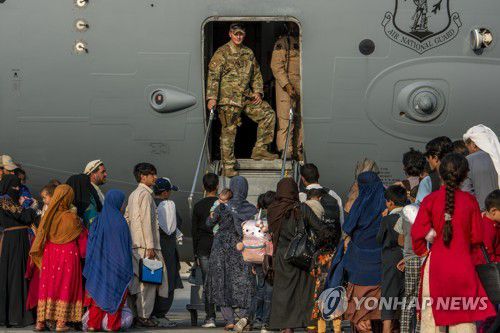 지난 22일 카타르 미 알 우데이드 공군기지에서 아프간인들이 미군 수송기에 오르기 위해 대기하고 있다. [미 공군 제공/EPA=연합뉴스 자료사진. 재판매 금지]