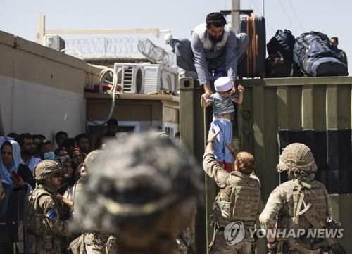 카불 공항서 영국군에 아이 건네는 아프간 남성    (카불 AP=연합뉴스) 이슬람 무장세력 탈레반이 장악한 아프가니스탄 수도 카불의 하미드 카르자이 국제공항에서 26일(현지시간) 국외로 탈출하려는 한 아프간 남성이 아이를 영국군 낙하산 부대원에게 건네고 있다. 영국 국방부는 지금까지 자국민과 아프간인 1만4천500여 명을 대피시켰다고 밝혔다. [미 육군 제공]