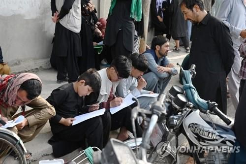 출국 서류 작성에 분주한 아프간인들지난달 19일(현지시간) 아프가니스탄 카불의 영국ㆍ캐나다 대사관 앞에 모인 아프간인들이 출국에 필요한 서류를 작성하는 모습. 본 기사와 관련 없음. [AFP=연합뉴스 자료사진]