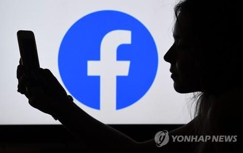 미국에서 페이스북 로고 앞에서 스마트폰을 보는 시민 [AFP=연합뉴스]