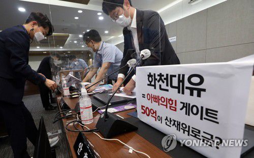 화천대유 관련 피켓 부착하는 더불어민주당(세종=연합뉴스) 김주형 기자 = 더불어민주당 관계자들이 6일 정부세종청사에서 열린 국회 환경노동위원회의 고용노동부에 대한 국정감사에 앞서 여당위원 좌석에 화천대유는 아빠의힘 게이트가 적힌 피켓을 부착하고 있다. 2021.10.6 [공동취재] kjhpress@yna.co.kr