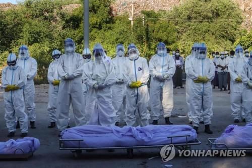만달레이의 코로나19 사망자 시신 앞에서 개인보호장비(PPE)를 입은 자원봉사자들이 기도하고 있다.(자료사진) [AFP=연합뉴스] [2021.07.27 송고]