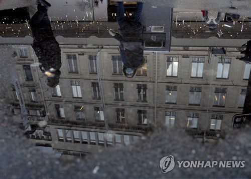 파리의 시민들2021년 12월 26일 프랑스 파리 거리에 고인 물에 마스크를 쓴 행인들의 모습이 비치고 있다. [AP 연합뉴스자료사진, 재판매 및 DB 금지]