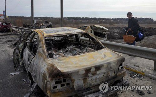 폭탄 맞아 불탄 차량 곁 지나는 우크라 이르핀 피란민(이르핀 AP=연합뉴스) 12일(현지시간) 우크라이나 수도권인 키이우(키예프) 북쪽 이르핀에서 한 주민이 폭탄에 맞아 불탄 뒤 곳곳에 널브러져 있는 차량 사이로 피란하고 있다. 수도 키이우로 통하는 길목인 이르핀에서는 러시아-우크라이나군 사이에 수일째 격렬한 시가전이 이어지고 있다.