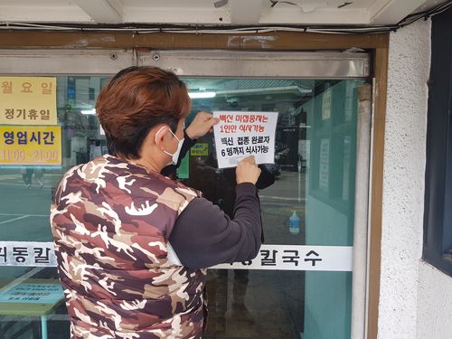 18일 서울 서대문구 연희동의 한 식당 직원이 거리두기 안내 표지를 교체하는 모습   [촬영 황수빈 수습기자]