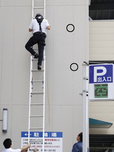 아베 피격 현장 90ｍ 떨어진 곳의 구멍(나라 교도=연합뉴스) 13일 오전 일본 나라현 나라시에서 경찰 관계자가 아베 신조 전 총리 피격 사건과 관련해 주차장 벽(우측 검은 원)에 생긴 구멍을 조사하고 있다. 구멍은 사건 현장에서 약 90ｍ 떨어진 곳에서 확인됐다.
