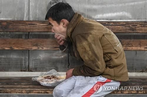 아프간 수도 카불의 버스정류장에서 음식을 먹는 아이.[AFP 연합뉴스 자료사진. 재판매 및 DB 금지]