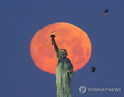 자유의 여신상 뒤로 뜬 슈퍼문[UPI 연합뉴스 자료사진. 재판매 및 DB 금지]
