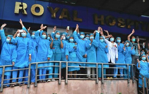 미얀마 최대 도시 양곤에서 플래시 몹 시위대를 향해 저항을 상징하는 세 손가락 경례를 하는 의료진. 2022.2.7.[AFP 연합뉴스 자료사진. 재판매 및 DB 금지]