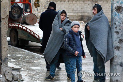 모포를 뒤집어쓰고 거리에 서 있는 시리아 남성과 어린이들[AFP 연합뉴스 자료사진. 재판매 및 DB 금지]