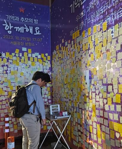 추모의 벽 앞에서 포스트잇에 글귀 쓰는 시민들[촬영 정윤주]