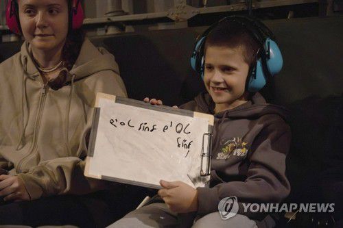 하마스에 인질로 잡혀있다 풀려난 이스라엘 소년(이스라엘 AP=연합뉴스) 27일(현지시간) 팔레스타인 무장 정파 하마스로부터 풀려난 이스라엘 소년이 자신의 누나와 함께 이스라엘 공군(IAF)의 헬기를 타고 귀국하고 있다. 소년이 들고 있는 화이트보드에는 '해외로 비행하기'라고 적혀있다. 하마스는 이스라엘과의 합의에 따라 휴전 첫날인 지난 24일부터 나흘간 이스라엘 인질 총 50명을 풀어줬다. 2023.11.28 ddy04002@yna.co.kr