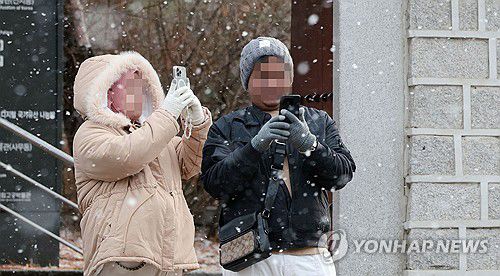 '눈이 반가워'(서울=연합뉴스) 김인철 기자 = 아침 기온이 영하로 내려가며 강추위의 날씨를 보이는 16일 오전 서울 종로구 경복궁 인근에서 외국인 관광객들이 내리는 눈을 촬영하고 있다. 2023.12.16 yatoya@yna.co.kr