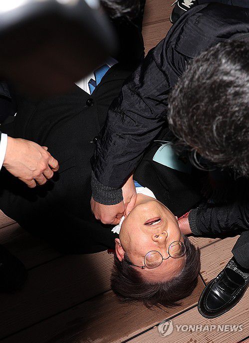 피습 당한 이재명 대표(부산=연합뉴스) 손형주 기자 = 더불어민주당 이재명 대표가 2일 오전 부산 강서구 가덕신공항 부지를 둘러본 뒤 왼쪽 목 부위 피습을 당해 바닥에 누워 병원 호송을 기다리고 있다. 2024.1.2 handbrother@yna.co.kr