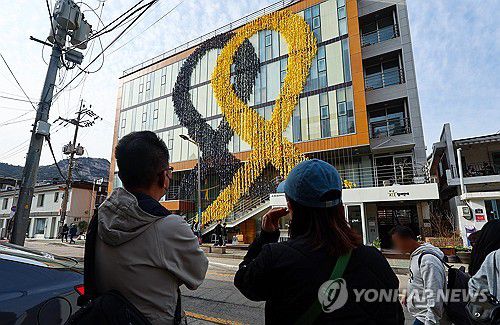 '세월호 10주기 앞두고'(서울=연합뉴스) 서대연 기자 = 세월호 참사 10주기를 보름여 앞둔 31일 오후 시민들이 서울 종로구 참여연대 건물 외벽에 설치된 대형 추모 리본을 바라보고 있다. 2024.3.31 dwise@yna.co.kr