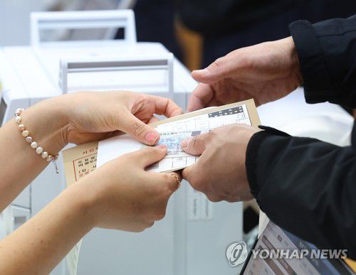 투표용지 받는 유권자(서울=연합뉴스) 김도훈 기자 = 4·10 총선 사전투표가 시작된 5일 오전 서울 여의동주민센터에서 한 유권자가 투표용지를 전달받고 있다. 2024.4.5 superdoo82@yna.co.kr