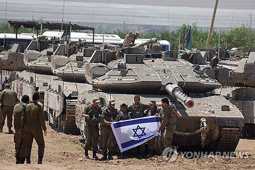 9일(현지시간) 가자지구 남단 미공개 위치에서 이스라엘 국기를 들고 사진찍는 군인들[EPA 연합뉴스 자료사진. 재배포 및 DB 금지]