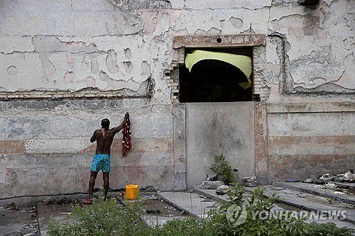 폐허처럼 변한 아이티 극장에서 샤워(포르토프랭스 EPA=연합뉴스) 28일(현지시간) 아이티 포르토프랭스 렉스 극장에서 한 남성이 몸을 씻고 있다. 2024.5.29