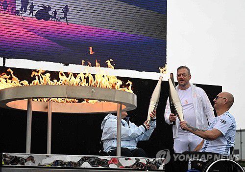 2024 파리 패럴림픽 성화 채화(에일즈베리[영국] AFP=연합뉴스) 영국의 헬렌 레인스퍼드(왼쪽)와 그레고르 이완(오른쪽), 앤드루 파슨스 IPC 위원장이 24일(현지시간) 영국 스토크맨더빌에서 2024 파리 패럴림픽 성화를 채화하고 있다.