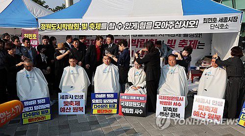 세종시의원 삭발식(세종=연합뉴스) 김준범 기자 = 국민의힘 소속 세종시의원들이 8일 오후 세종시청 앞에서 삭발식을 하고 있다. 이들은 최민호 세종시장의 핵심 공약인 정원도시박람회와 빛 축제 개최를 위한 예산안 통과를 촉구하며 삭발식을 진행했다. 2024.10.8 psykims@yna.co.kr