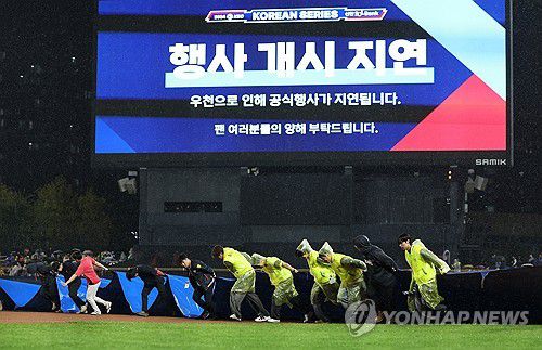 다시 방수포(광주=연합뉴스) 김도훈 기자 = 21일 2024 신한 SOL뱅크 KBO 포스트시즌 한국시리즈 1차전 삼성 라이온즈와 KIA 타이거즈의 경기가 예정된 광주 기아챔피언스필드에서 경기장 관계자들이 비가 다시 거세지자 철거했던 방수포를 다시 설치하고 있다. 2024.10.21 superdoo82@yna.co.kr