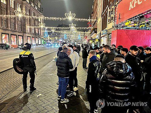 폭력 사태 현장 정리하는 경찰(암스테르담 로이터=연합뉴스) 8일(현지시간) 새벽 네덜란드 암스테르담 시내에서 경찰들이 이스라엘 축구 팬들을 보호하고 서 있다. 2024.11.09