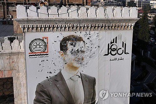 탄흔 투성이인 바샤르 알아사드 시리아 대통령의 사진[AFP 연합뉴스 자료사진. 재판매 및 DB 금지]